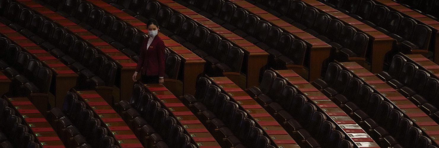 A hostess gives a final check on the reports placed on tables ahead of the closing session of the National People's Congress (NPC) at the Great Hall of the People in Beijing, Monday, March 11, 2024.